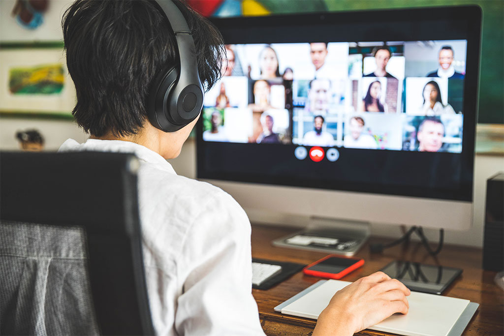 Person with headphones sitting in front of a computer screen on a video call.