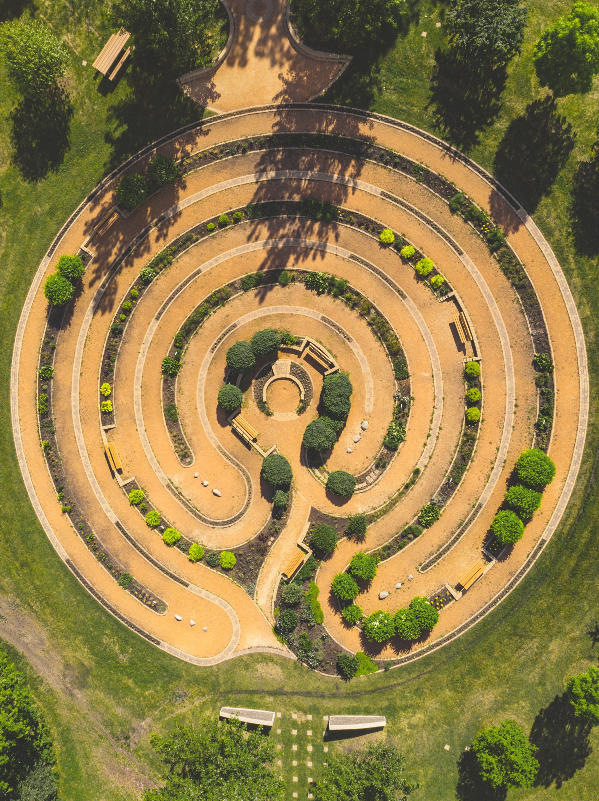 Aerial shot of a meditative circular pathway with shrubs and other greenery on bright sunny summer day. 
